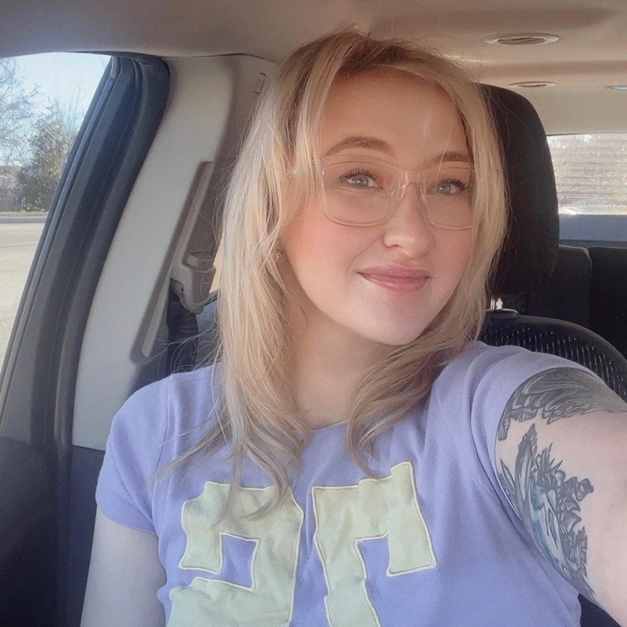 Cheyenne smiling with shoulder-length blonde hair and clear-framed glasses